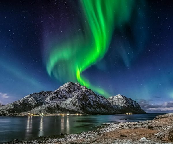 green aurora borealis over snow covered mountain